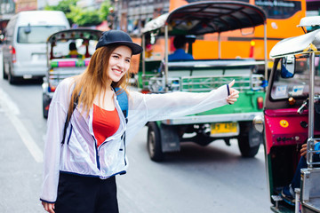 Asian white women wear red t-shirts and capes. Calling the taxi Chinatown, Bangkok, Thailand
