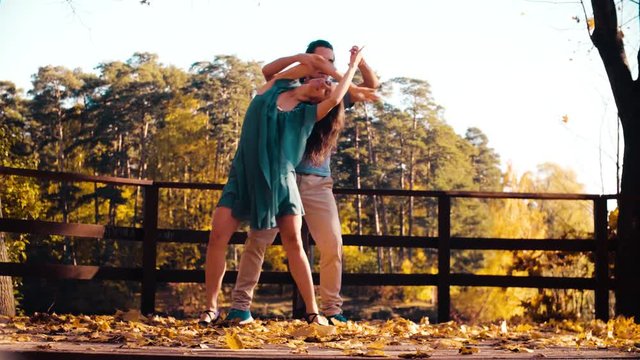 Young happy couple dancing on the wooden bridge. Golden autumn