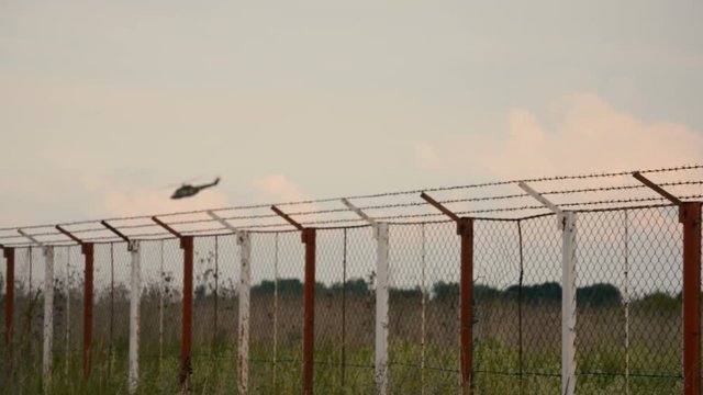 Blurred military helicopter and barbe wire fence