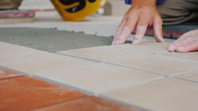 Workers laying tile on the floor, close-up