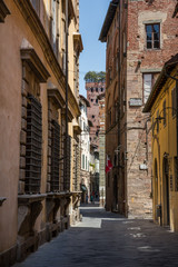 Fototapeta na wymiar Lucca Italy July 4th 2015 : Narrow streets leading to the Guinigi tower in Lucca Tuscany