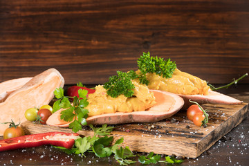 Mashed sweet potato with pepers chilli, tomatoes and greenery on a dark wooden board background. Horizontal.
