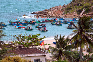 Rural fishing village in Central Vietnam. Sandy beach and rocky cape. Fishing boats at the shoreline. Near Quy Nhon, Vietnam.