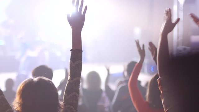 Audience applauds clapping hands at the concert flashing spotlights to performer