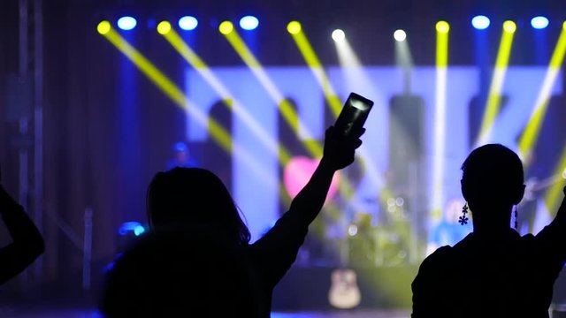 Swaying hands in air with mobile phones lights girl fans silhouette at the concert