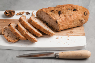 Freshly healthy Sliced bread with walnuts and raisins on cutting board on gray stone background. Copy space. Horizontal.