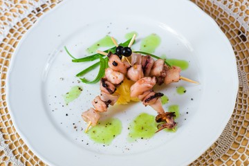 Three skewer with seafood mix on white plate.