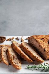 Freshly healthy Sliced bread with walnuts and raisins on cutting board on gray stone background. Copy space. Vertical. Selective focus.