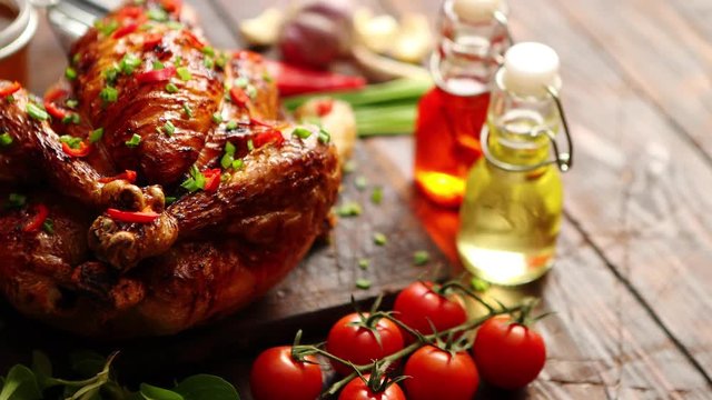 Roasted whole chicken or turkey served on wooden chopping board with chilli pepers and chive. With ingredients on sides. Shot from above with copy space for text.