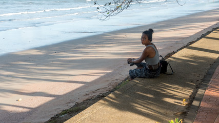 Woman sitting on sidewalk at beach