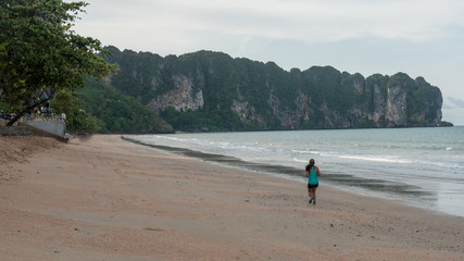 Woman jogging on beach with mountains in background