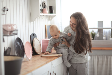 Mom hugging baby boy playing with son in kitchen