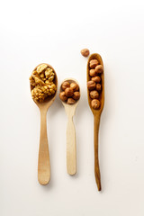 Walnuts and hazelnuts in wooden spoons isolated on white background. Top view