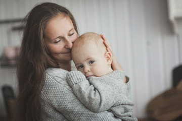 Mom hugging baby boy playing with son in kitchen
