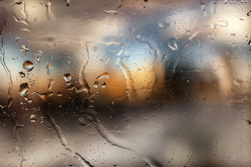 Colorful bokeh with street light at night. Raindrops on car windshield, traffic in the city on a rainy day. Blur background. Selective focus.