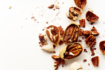 Cracked and opened pecan nuts and nuts in shell. Overhead wiew on white background with copy space