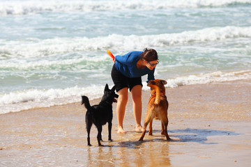 Mature Woman  playing with her dogs on the beach