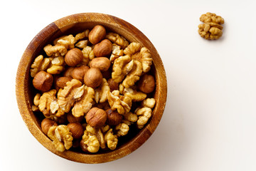 Overhead image of assorted nuts in wooden bowl on white background with copy space