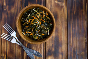 Salad with seaweed, celery and carrots in the brown bowl on the  wooden background.Copy space.Top view.