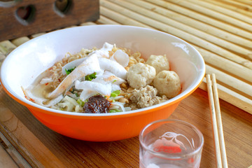 Noodles in an orange bowl placed on a table.