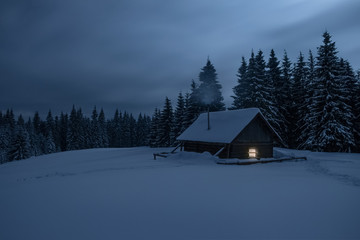 Wooden cabin under stars. Lights shines through the window from inside of the house. Night...