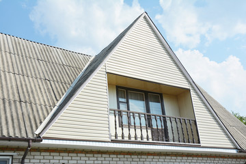 Building attic house construction with asbestos roof, cozy balcony and siding facade