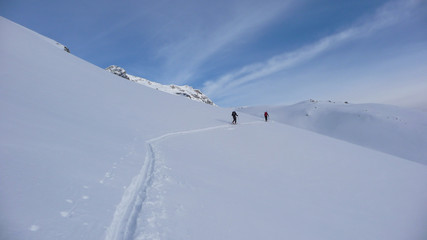backcountry skiers on a climb in the Hohen Tauern region of the Austrian Alps putting in new tracks on their way to a distant mountain peak