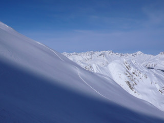 picturesque deep winter mountain landscape in the Alps of Switzerland with backcountry ski tracks in fresh powder