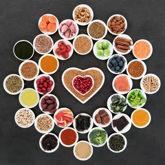 Superfood to slow the ageing process including fruit, vegetables, herbs, spices, fruit, fish, supplement powders, seeds and nuts on slate. High in antioxidants, anthocyanins, dietary fibre & omega 3.