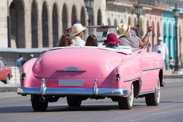 Schöner rosa Oldtimer/Cabriolet mit fröhlicher Gruppe auf Kuba (Karibik)