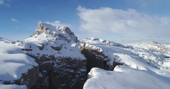 Going up aerial toward majestic Cinque Torri mounts discovering valley. Sunny day with cloudy sky.Winter Dolomites Italian Alps mountains outdoor nature establisher.4k drone flight