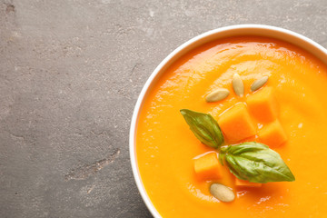 Bowl with tasty pumpkin soup and space for text on gray background, top view