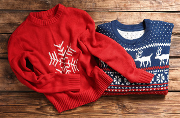 Christmas sweaters with pattern on wooden background, top view © New Africa