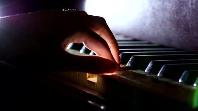Playing the piano - fingers of a pianist in the rays of light