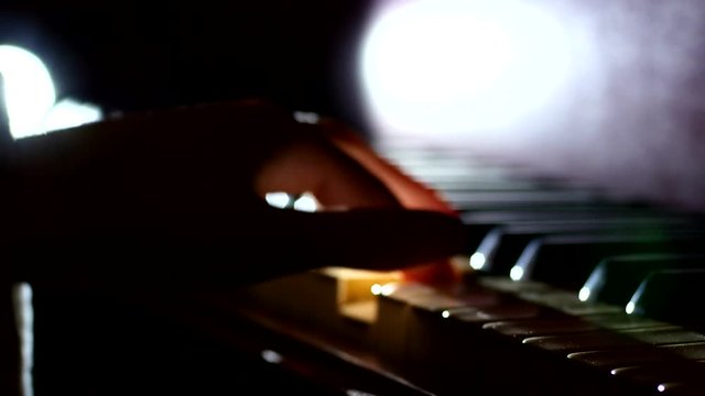 Playing the piano - fingers of a pianist in the rays of light