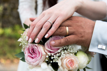 Obraz na płótnie Canvas mains des mariés avec leur alliances sur le bouquet coloré de la mariée