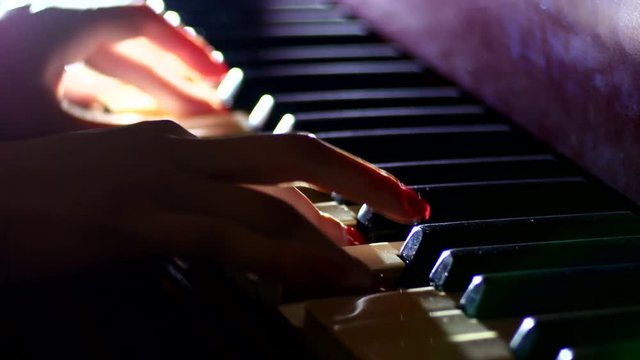 Playing the piano - fingers of a pianist in the rays of light