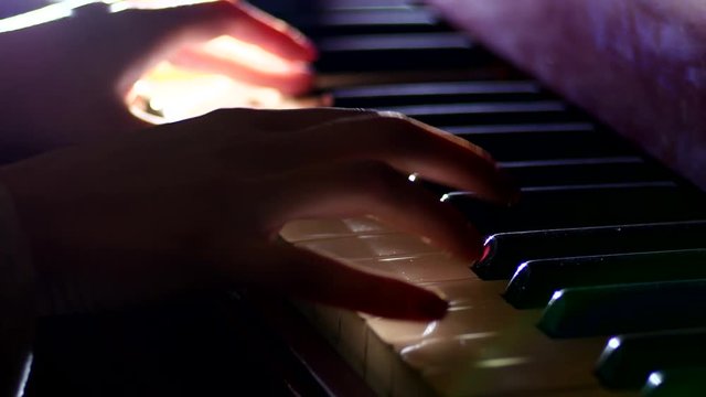 Playing the piano - fingers of a pianist in the rays of light