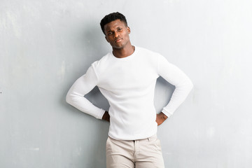 Young afro american man posing on textured grey wall