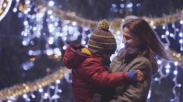 Portrait of mother and child dancing in front of Christmas tree outdoors