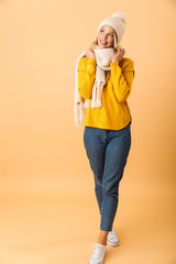 Happy woman wearing scarf and hat posing isolated over yellow wall background.