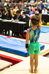 Portrait of a gymnast child waving to the jury after competing