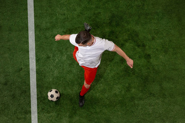 Football player tackling for ball over green grass background. Professional football soccer player in motion at studio. Fit jumping man in action, jump, movement at game.