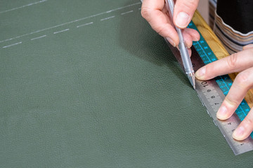 craftsman draws pattern on leather using ruller