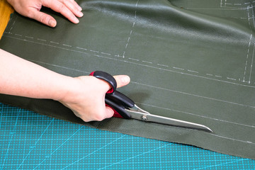 craftsman cuts green leather using scissors