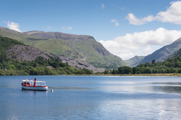 Fototapeta na wymiar A boat on the tranquil blue waters of Llyn padarn, a naturally formed lake in Snowdonia, north Wales