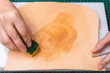 craftsman dampens the ornament on leather