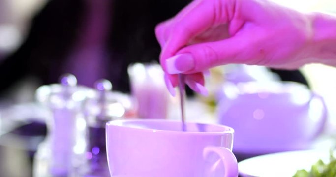 Drink tea, a hand mixing sugar in a cup