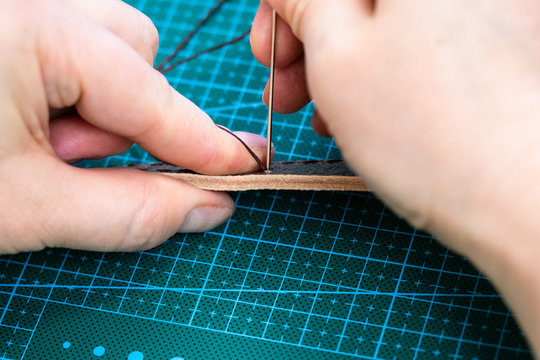 craftsman stitches the belt for leather handbag