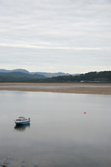 Fototapeta na wymiar A small blue boat in a bay art low tide, North Wales